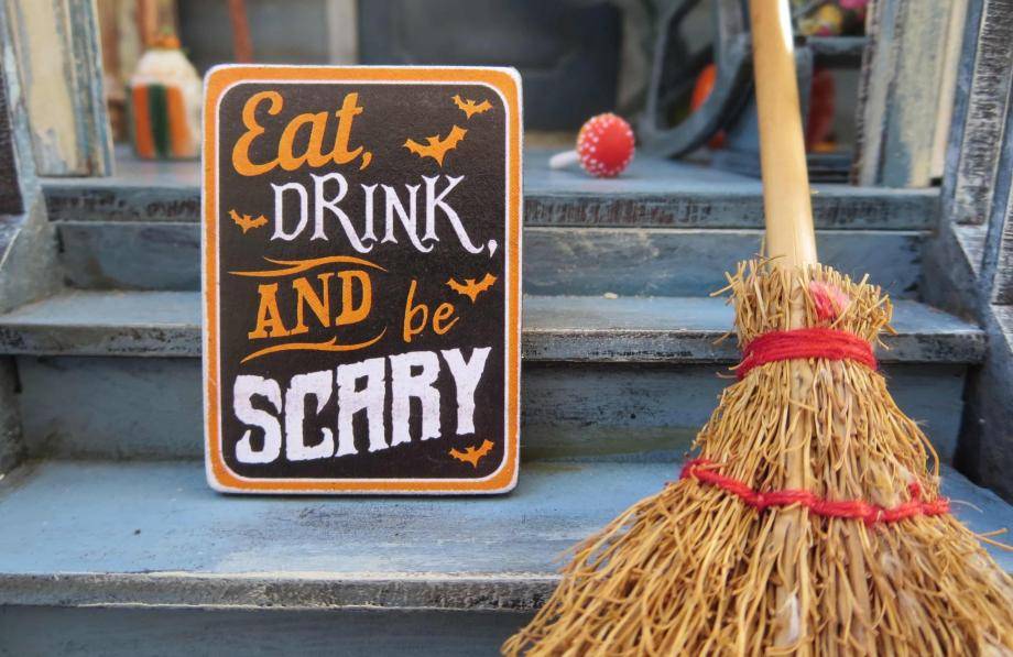 sign that says "eat drink and be scary" next to broom on stairs